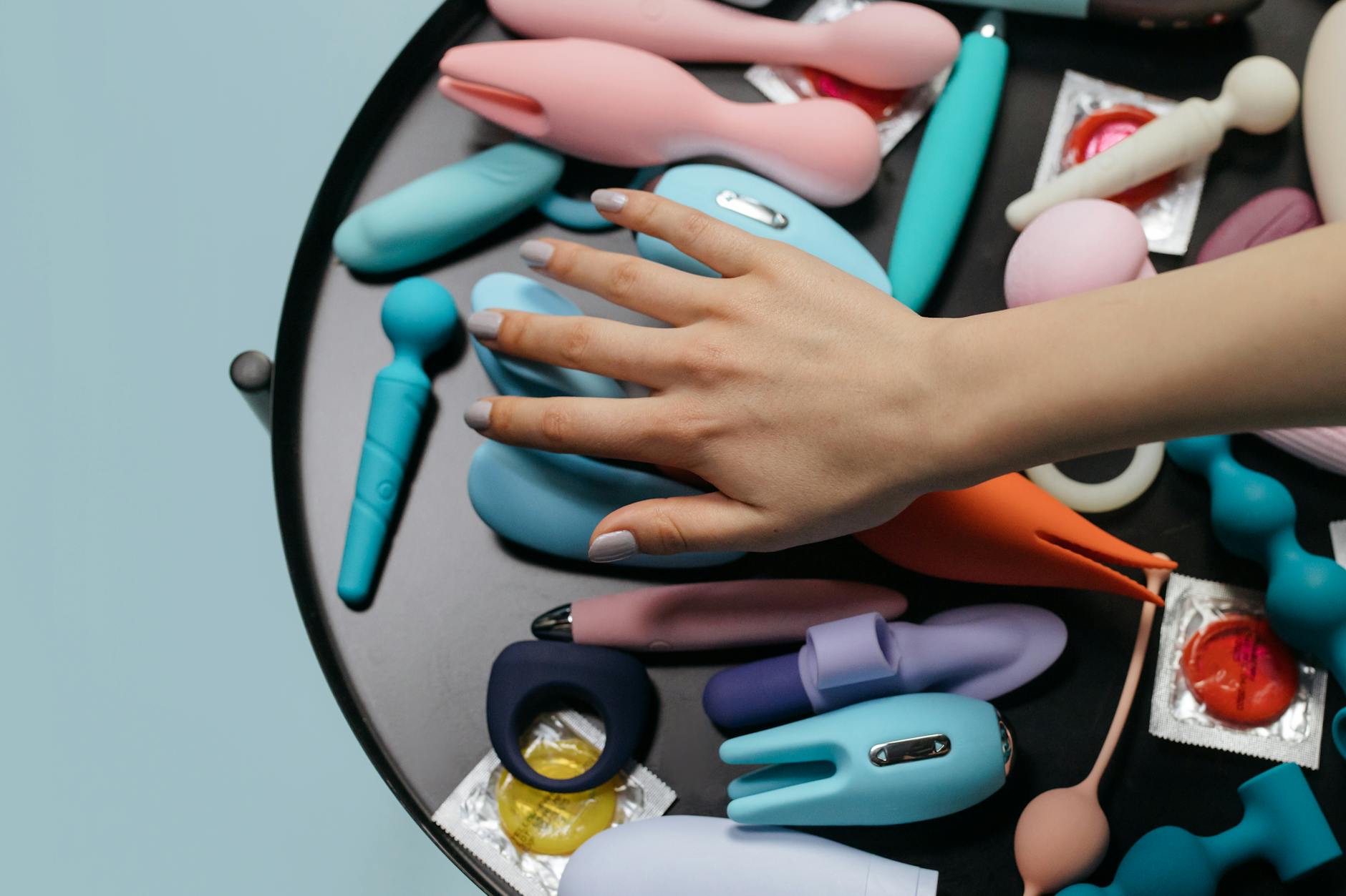 A blue silicone clitoral vibrator held in hand, representing self-pleasure and intimate connection