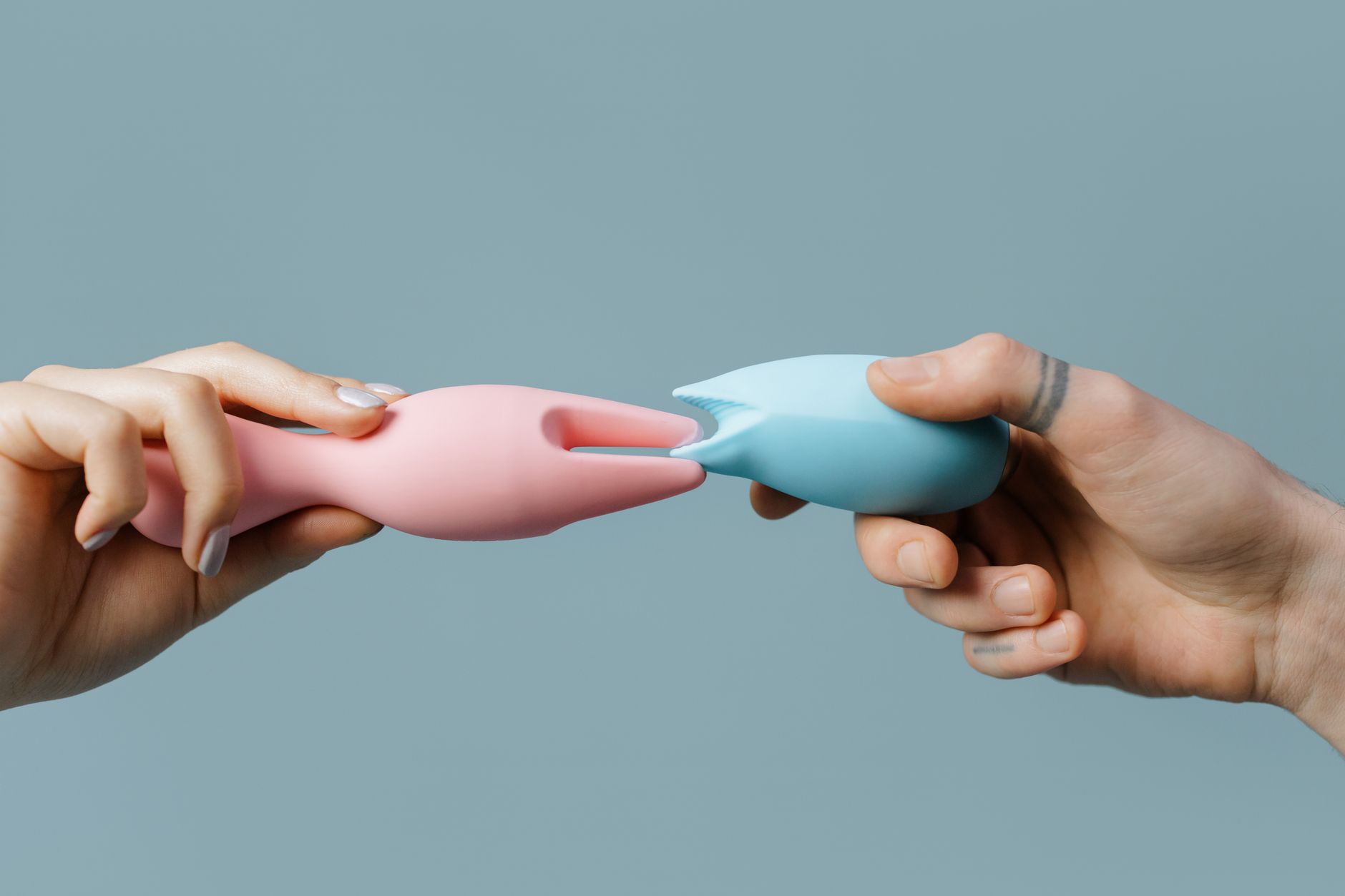 Hand holding a clitoral vibrator against a purple backdrop, showcasing modern pleasure tools