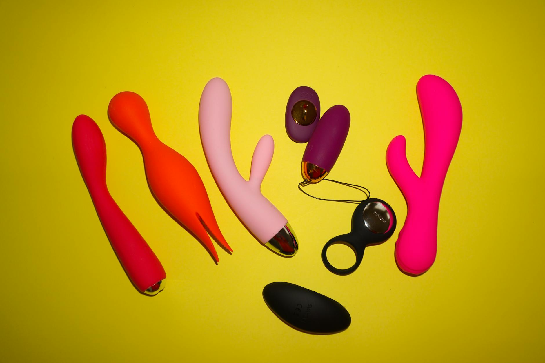 Close-up array of colorful adult toys and vibrators on white surface